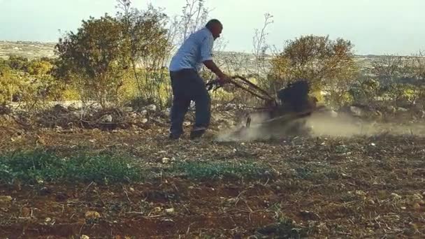 Ein einzelner männlicher Bauer pflügt sein Feld mit einer benzinbetriebenen manuellen Pflügemaschine - Filmmaterial, Video