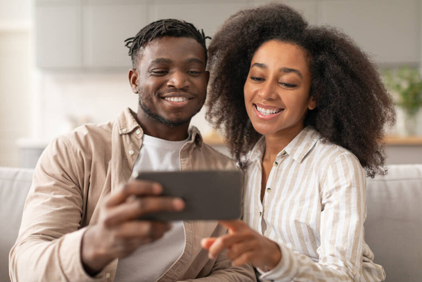 Veselý černý milennial pár pomocí Smartphone dělat Selfie nebo video hovor, Uživatelé telefonu prohlížení internetu, Dotykový mobilní telefon obrazovky doma uvnitř. Mobilní aplikace, koncept životního stylu Gadgetu - Fotografie, Obrázek