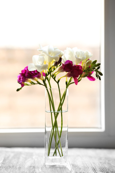 Beautiful spring flowers in glass vase on windowsill background - Photo, Image
