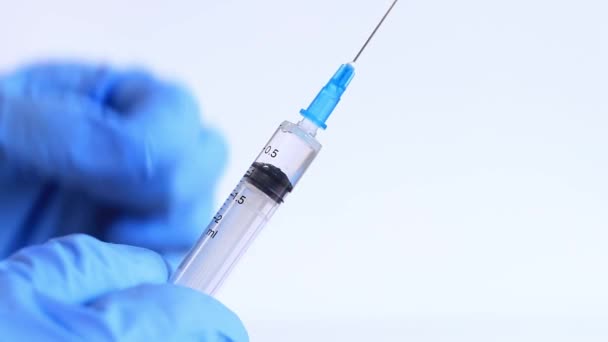 La main d'une femme dans un gant médical bleu tient une seringue. Infirmière ou médecin avec une seringue de 2 ml. Vaccination. Injection - Séquence, vidéo
