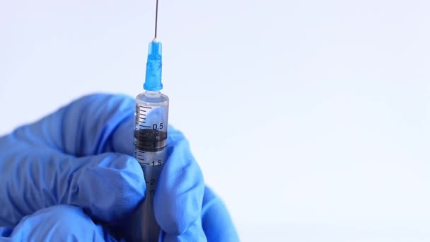 La main d'une femme dans un gant médical bleu tient une seringue. Infirmière ou médecin avec une seringue de 2 ml. Vaccination. Injection - Séquence, vidéo