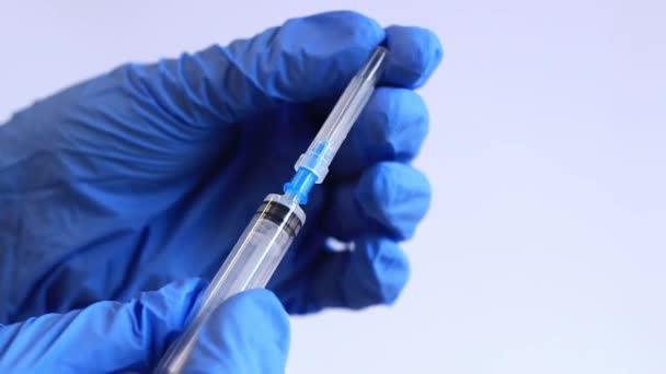 Die Hand einer Frau in einem blauen Medizinhandschuh hält eine Spritze. Krankenschwester oder Arzt mit einer 2 ml-Spritze. Impfen. Injektion - Filmmaterial, Video