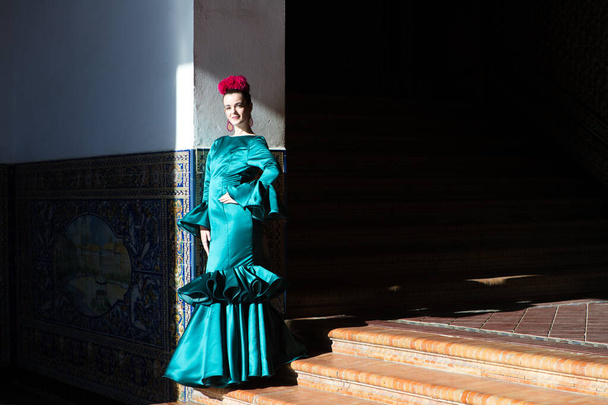 Mujer joven y hermosa con vestido de volantes verdes y baile flamenco está en las escaleras de la plaza de España en Sevilla, andalusia. La mujer tiene arte y es típica de España - Foto, imagen