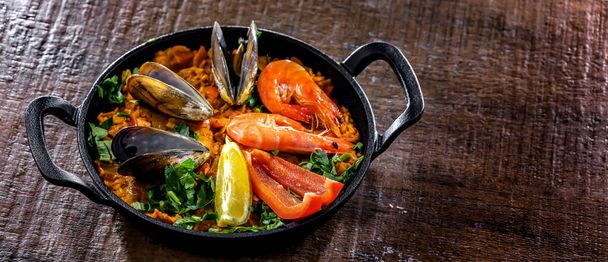 Seafood paella served in a cast iron pan. - Foto, afbeelding