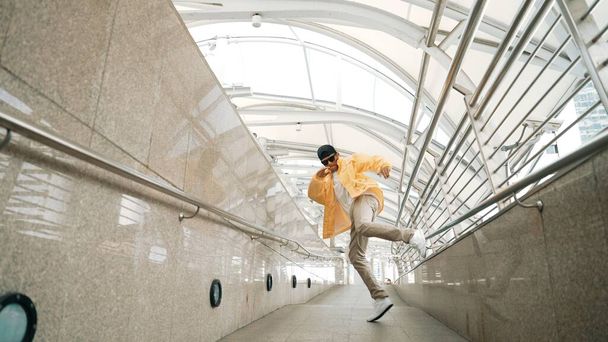 Έξυπνος Ασιάτης χίπστερ που περπατάει χορεύοντας στο στενό διάδρομο. Κοντινό πλάνο χορευτή break dancer εξάσκηση break dance. Επαγγελματίας άνθρωπος κινείται προς τη μουσική. Υπαίθριο άθλημα 2024. Ελαφρώς. - Φωτογραφία, εικόνα