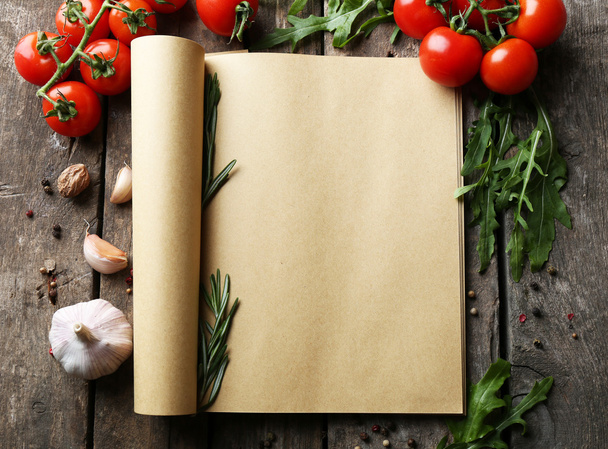 Open recipe book with fresh herbs, tomatoes and spices on wooden background - Фото, изображение