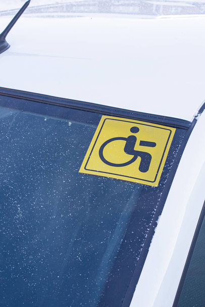 Un autocollant sur le pare-brise d'une voiture avertissant que le conducteur est un conducteur handicapé. - Photo, image