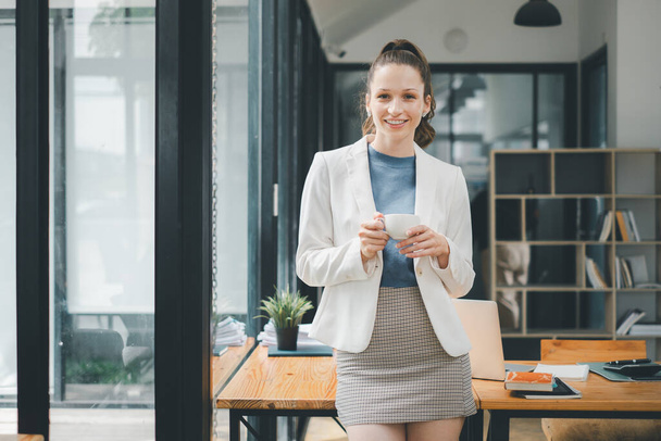 Biznes kobieta koncepcja, Stojąca businesswoman korzystających z kawy z przyjemnym uśmiechem w nowoczesnym i stylowym otoczeniu biurowym - Zdjęcie, obraz