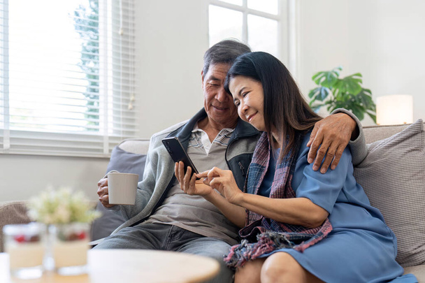Muotokuva Aasian ihana vanhempi pari käyttää älypuhelinta yhdessä video chattailuun perheen kanssa olohuoneessa kotona.. - Valokuva, kuva