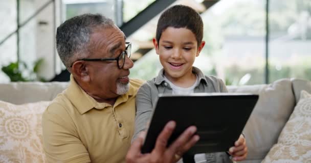 Tablet, εκπαίδευση ή παιχνίδι με τον παππού και το αγόρι στον καναπέ στο σαλόνι του σπιτιού μαζί για επίσκεψη. Οικογένεια, τεχνολογία ή εφαρμογή κοινωνικής δικτύωσης με τον ηλικιωμένο άνδρα και τον εγγονό στο διαμέρισμα για μάθηση. - Πλάνα, βίντεο