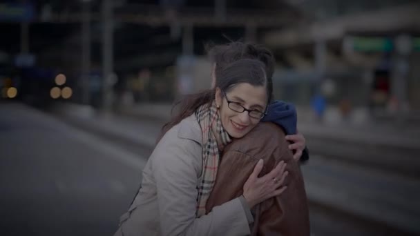 Reünie van alleenstaande moeder en tienerzoon knuffelen op spoorwegplatform  - Video