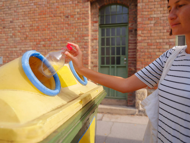 nainen heittää muovipullo Kierrätys bin seistä Euroopan kadulla. Jätteiden lajittelu roskat ennen pudota roskakoriin pelastaa maailman, ympäristön hoito. Saasteiden kierrätyksen hallinta - Valokuva, kuva