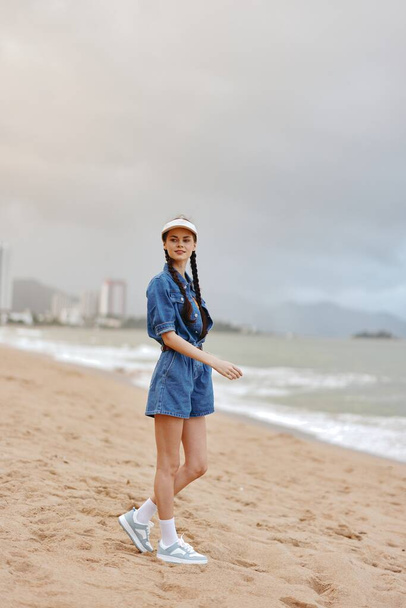 Samotna, smutna i stojąca: ładna młoda kobieta w niebieskiej sukience na plaży, patrząca na ocean ze smutnym wyrazem twarzy, korzystająca z relaksu w tropikalnym raju - Zdjęcie, obraz