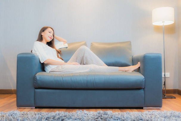 Ritratto bella giovane donna asiatica rilassarsi sul divano in salotto interno - Foto, immagini