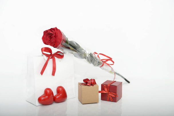 Festive background from a gift bag, a box with a bow, a preserved rose and hearts. Holiday gifts.Store display - Photo, Image