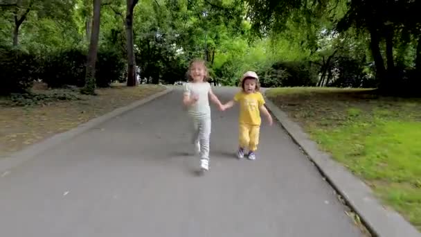 Parkta koşan iki küçük kız. Mutlu kız kardeşler, eğleniyorlar. Aile aktivitesi açık havada. - Video, Çekim