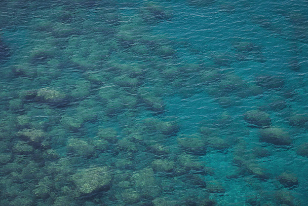 Vista aérea del tranquilo agua de mar turquesa y rocas de lava fundida del dron. Patrón de superficie marina y costa rocosa. Liguria, Italia. aguas turquesas del mar de Liguria. - Foto, imagen