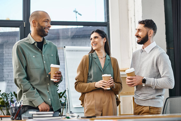 Un gruppo di colleghi in piedi intorno a un tavolo, impegnati in una discussione su tazze di caffè durante una pausa in ufficio. - Foto, immagini