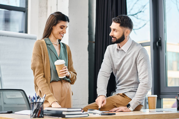 Een man en vrouw werken samen aan een project aan een bureau, nemen een pauze met koffie in een kantooromgeving. - Foto, afbeelding
