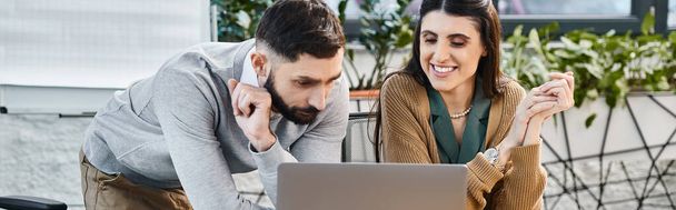 Um homem e uma mulher trabalham em um laptop em um ambiente de escritório corporativo, unidos em seu foco e determinação. - Foto, Imagem