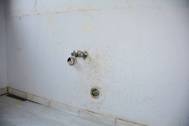 Muur met water- en stroomaansluiting in een keuken tijdens renovatie tijdens verhuizing - Foto, afbeelding