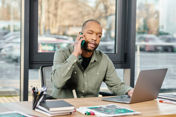 schwarzer Mann sitzt an einem Schreibtisch, voll beschäftigt mit einem Handyanruf, tief im Gespräch. - Foto, Bild