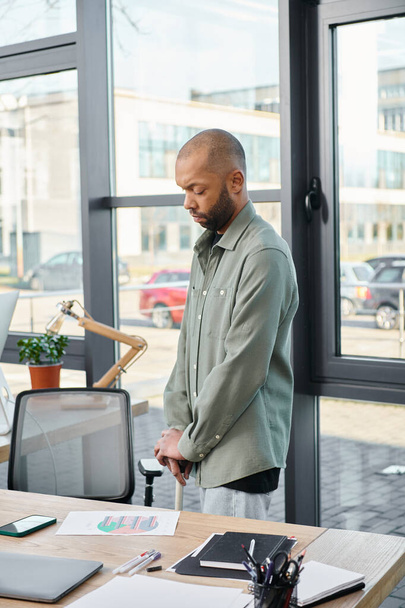Чоловік з міастенією в сучасному офісному приміщенні, впевнено стоїть перед ноутбуком, занурений у свою роботу. - Фото, зображення
