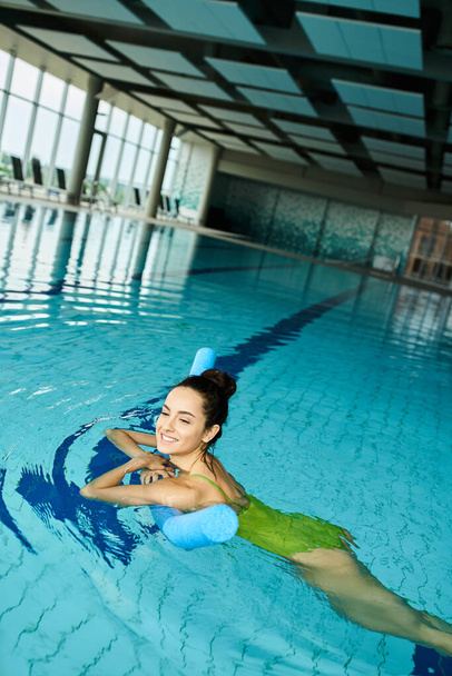 Потрясающая брюнетка, грациозно плавающая в крытом бассейне спа. - Фото, изображение