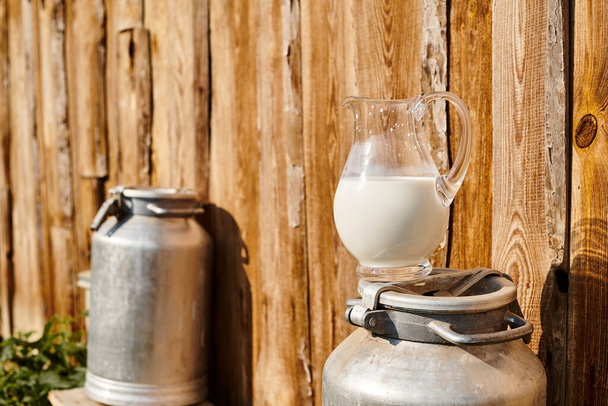 objeto foto de metal batido y frasco de leche fresca colocada fuera de la casa de pueblo cercana en la granja moderna - Foto, Imagen