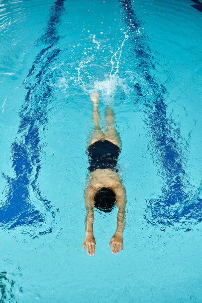 Eine Frau in Badebekleidung schwimmt friedlich in einem Pool mit blauem Wasser - Foto, Bild