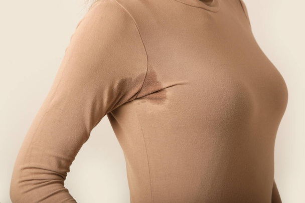  Close up image of woman in beige cotton turtleneck with sweat patch under armpit - Photo, Image