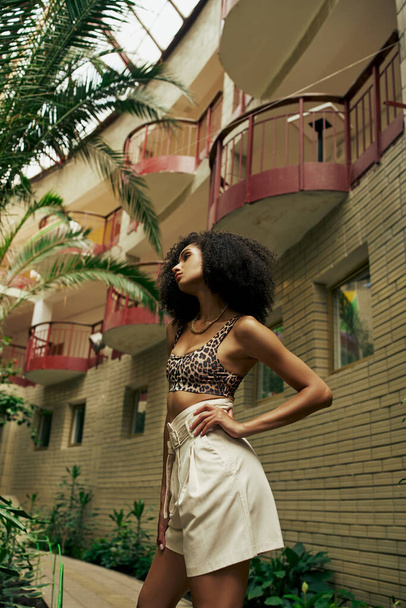 Confident black woman in chic style standing with hand on hip in atrium with botanical backdrop - Fotoğraf, Görsel
