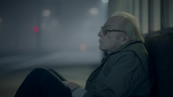 Przygnębiony i nieszczęśliwy Old Male Street Person Czekający na pomoc w mroźnej nocy - Materiał filmowy, wideo