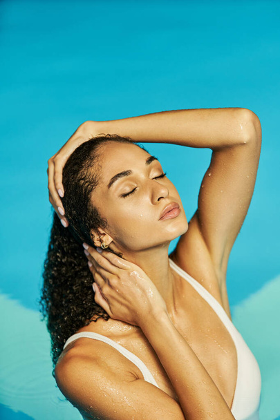 junge afrikanisch-amerikanische Frau im weißen Badeanzug findet Gelassenheit im kühlen blauen Poolwasser, geschlossene Augen - Foto, Bild