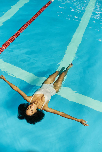 vista dall'alto della giovane donna afroamericana che nuota sulla schiena in acqua blu della piscina, tranquillità - Foto, immagini