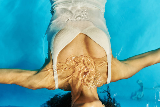 vista dall'alto della donna africana americana ritagliata che nuota sulla schiena in acqua limpida della piscina, tranquillità - Foto, immagini