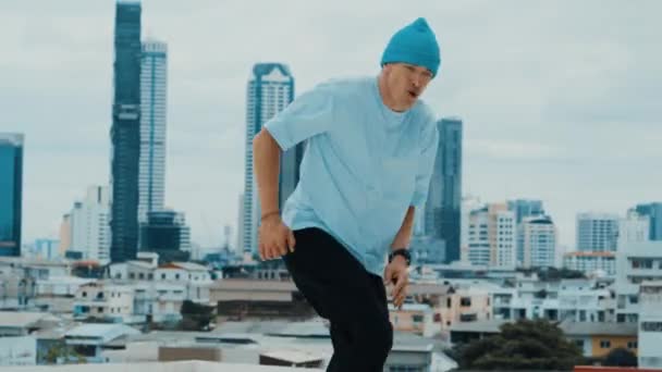 Ballerino di B-boy caucasico professionista che pratica il ballo di strada sul tetto con città o urbano. Motion shot di giovane uomo che esegue street dance facendo posa congelare. Sport all'aria aperta 2024. hiphop. - Filmati, video
