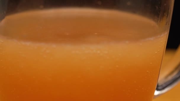 Macro shot van fijne belletjes rijzen op in een glas met oranje vloeistof abstracte bel achtergrond vitamine C limonade - Video