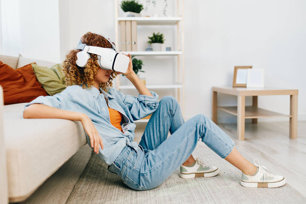 Virtuální realita zábava: Usmívající se žena těší futuristické VR hry na pohovce doma - Fotografie, Obrázek