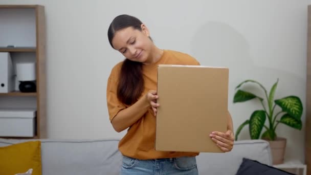 iloinen nainen tarttuu hänen paketti, johon sisältyy online-ostoksia tyytyväisyys hänen kauan odotettu toimitus saapuu - Materiaali, video