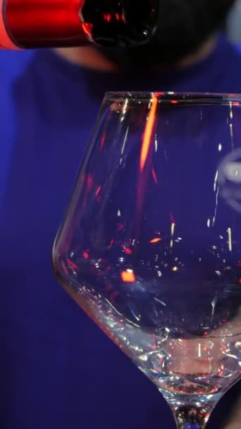 крупним планом знімок вертикальної відео пляшки червоного вина вливається в келих в ресторані. Червоне вино, спосіб життя, алкоголь - Кадри, відео