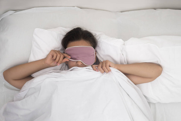 bonita mulher acorda levantando máscara de sono no quarto do apartamento acordar depois de descansar  - Foto, Imagem