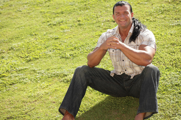 Hombre feliz sentado en la hierba
 - Foto, imagen