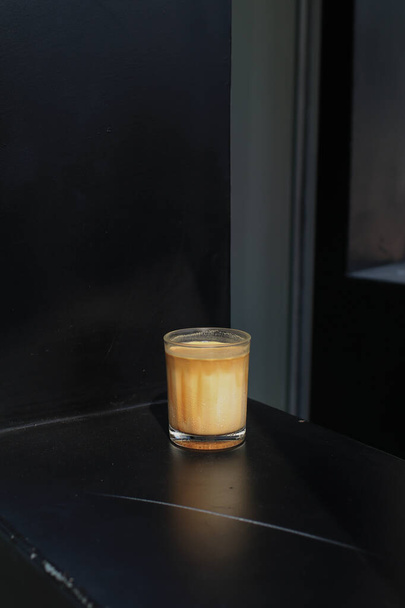 Café sucio colocado en la mesa negra durante el desayuno. Copa de café espresso mezclado con leche fresca fría en cafetería cafetería y restaurante - Foto, Imagen