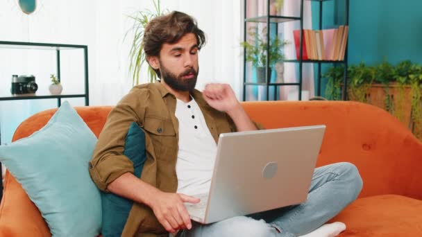 Közel-keleti férfi ül a kanapén nézi a kamerát, hogy video webkamera konferencia hívás barátaival vagy családjával élvezi a kellemes beszélgetést. Fiatal srác nevet integetett hello otthon szoba lakás - Felvétel, videó