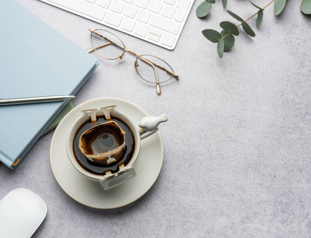 Skleněný šálek čerstvě uvařené kávy s praktickým kávovým filtrem na kancelářském stole. Káva přestávka, rychlý způsob, jak vařit horký nápoj - Fotografie, Obrázek