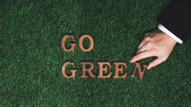 Gehen Sie grün und retten Sie die Welt mit umweltfreundlichen Anstrengungen. Botschaft Go Green Brief von Geschäftsmann Hand arrangiert, um das Ökobewusstsein für eine nachhaltige Zukunft mit biophilen Design Hintergrund zu fördern. Kreisel - Foto, Bild