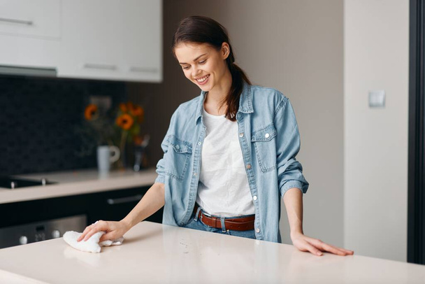 Domů Krása: Mladý běloch žena čištění kuchyňský stůl s hadrem a sprejem - Fotografie, Obrázek