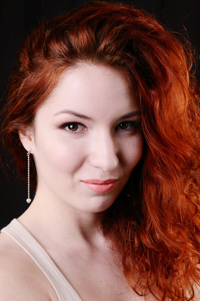 Mooie jonge redhead vrouw met perfecte overdag make-up en lange zilveren oorbellen glimlachend speels - Foto, afbeelding