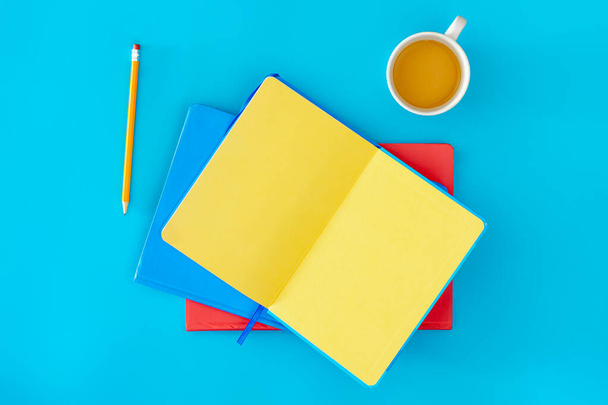 着色されたノートパッドと青い背景,トップビューのコーヒー. 空白のメモ帳を開き,スペースをコピーする. - 写真・画像